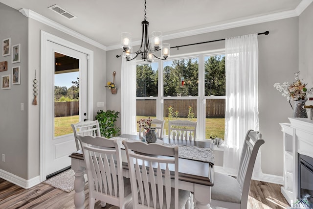 dining area with hardwood / wood-style flooring, a notable chandelier, and crown molding