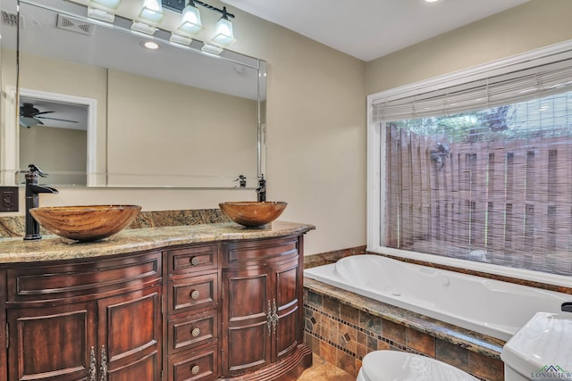 bathroom featuring double vanity, ceiling fan, a bath, and a sink