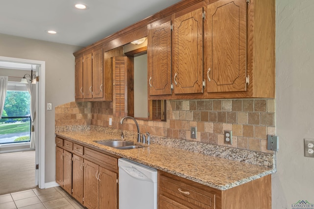 kitchen featuring a sink, backsplash, white dishwasher, brown cabinets, and light tile patterned floors