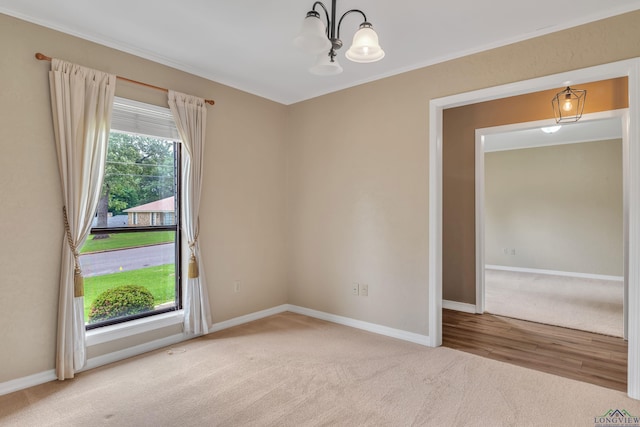 carpeted spare room featuring baseboards, a chandelier, and ornamental molding