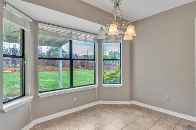 unfurnished dining area with light tile patterned flooring, baseboards, and a notable chandelier