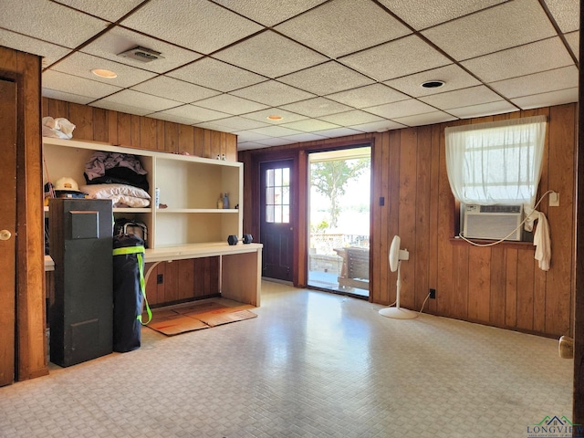 office space with a drop ceiling, cooling unit, and wood walls