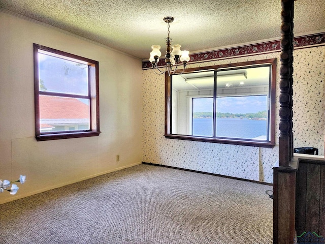 empty room with a water view, carpet floors, a textured ceiling, and an inviting chandelier