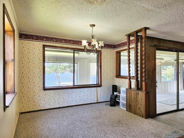 spare room featuring carpet, a textured ceiling, and a notable chandelier