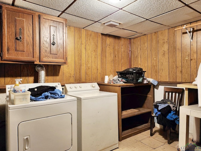 laundry area with washer and dryer, wooden walls, and cabinets