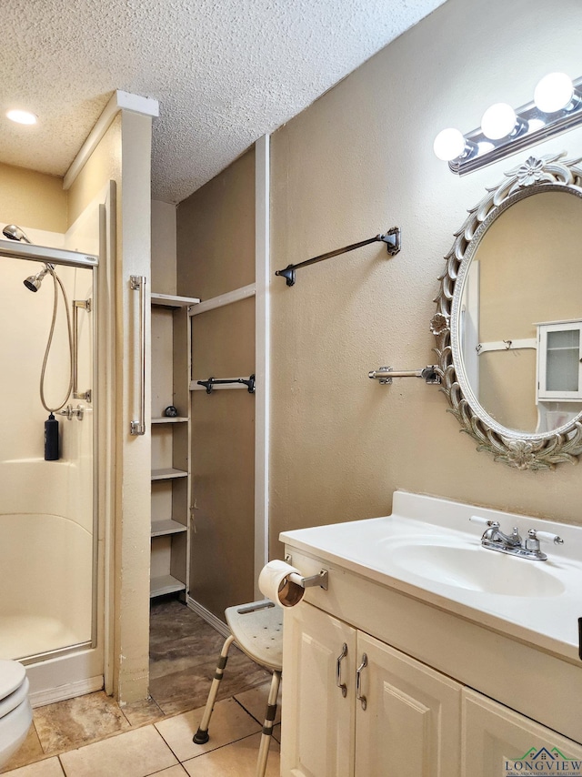 bathroom with vanity, a textured ceiling, toilet, and a shower with door