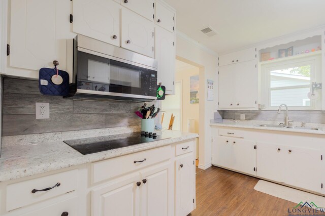 500 Jasper Dr, Marshall, TX 75672 - kitchen featuring visible vents, black electric cooktop, stainless steel microwave, a sink, and backsplash
