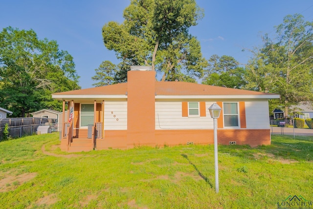 view of front of house featuring fence, a chimney, and a front lawn