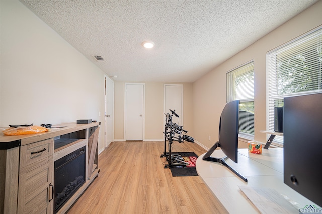 workout area featuring a textured ceiling and light hardwood / wood-style floors