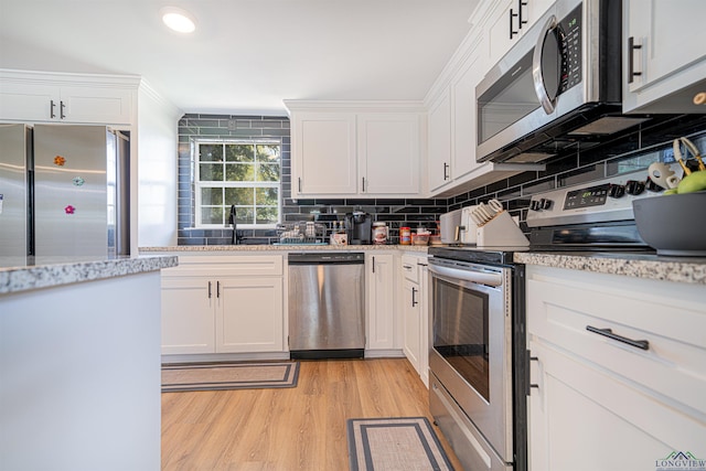 kitchen featuring white cabinets, decorative backsplash, light stone countertops, light wood-type flooring, and appliances with stainless steel finishes