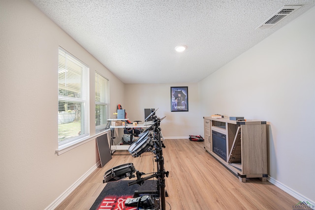 exercise area with a textured ceiling and light wood-type flooring