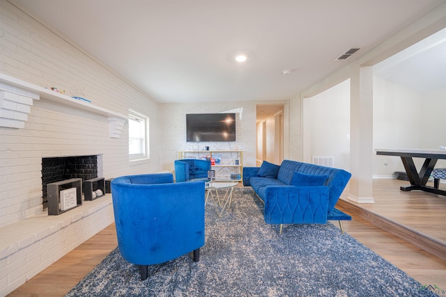 living room with hardwood / wood-style floors, a fireplace, and brick wall