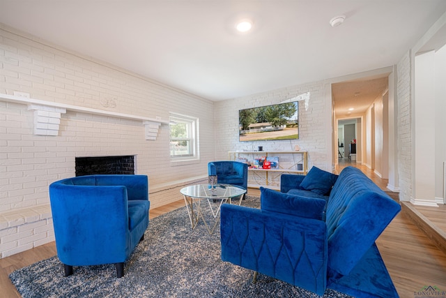 living room with hardwood / wood-style flooring, a fireplace, and brick wall