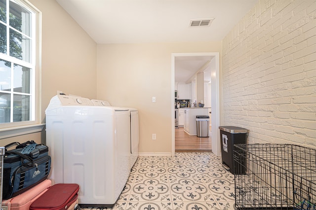 washroom featuring brick wall and washing machine and clothes dryer