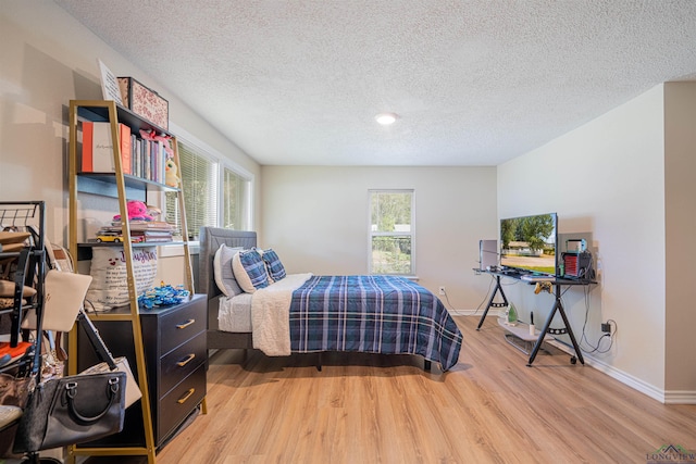 bedroom with a textured ceiling and light wood-type flooring