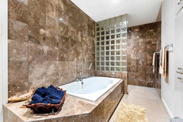 bathroom with tile patterned floors, tiled bath, and tile walls