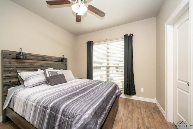 bedroom with ceiling fan, baseboards, and wood finished floors