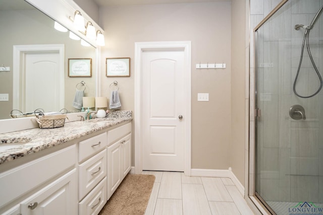 bathroom with a shower stall, vanity, and baseboards