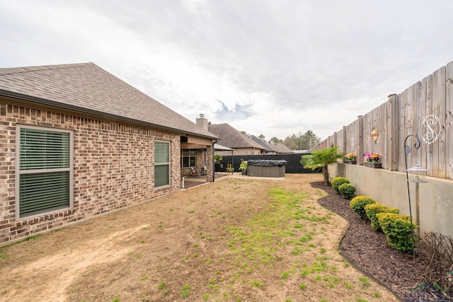 view of yard with a patio, a fenced backyard, and a hot tub