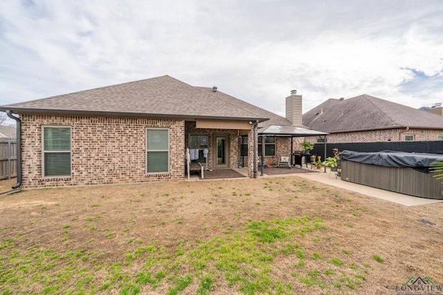 back of property with a patio, brick siding, fence, a gazebo, and roof with shingles