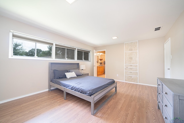 bedroom featuring connected bathroom and light hardwood / wood-style floors