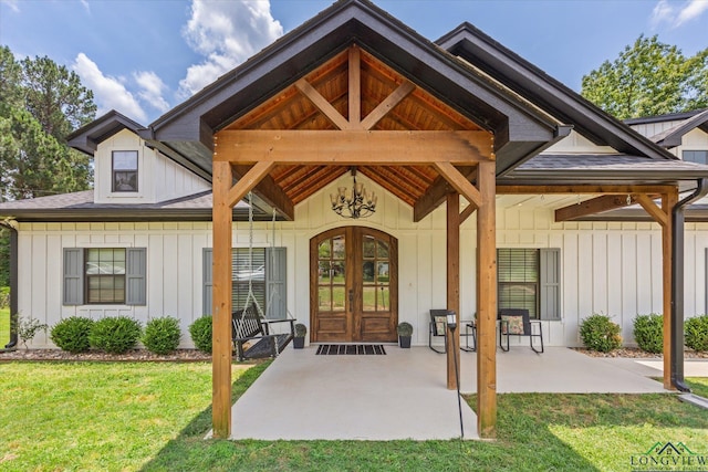 223 Circle Ridge Dr, Gilmer, TX 75645 - view of exterior entry with board and batten siding, a lawn, and french doors