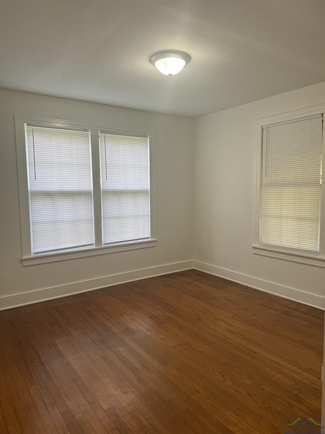 unfurnished room with plenty of natural light and dark hardwood / wood-style floors