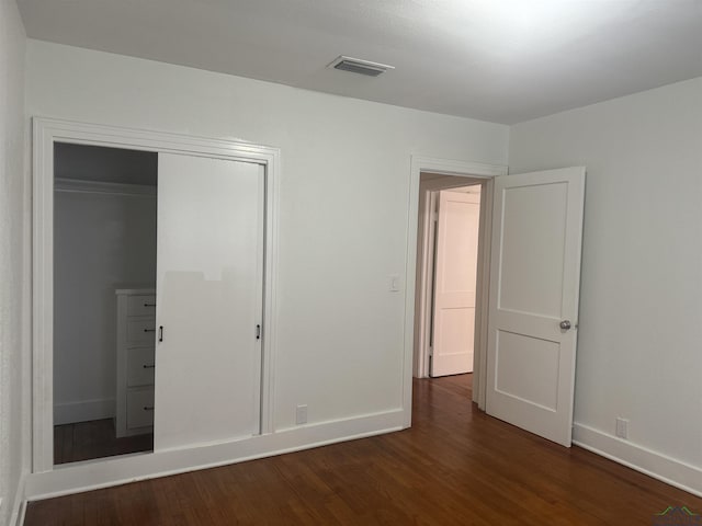 unfurnished bedroom featuring dark hardwood / wood-style flooring and a closet