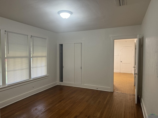 unfurnished bedroom with dark hardwood / wood-style flooring and a closet