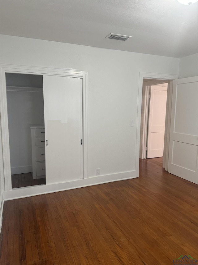 unfurnished bedroom featuring dark hardwood / wood-style flooring and a closet