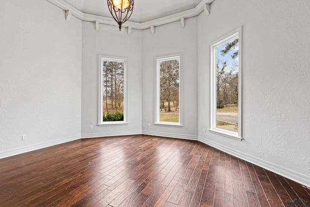 empty room with a textured wall, baseboards, and wood finished floors