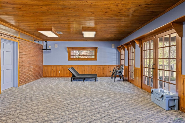 unfurnished room with a wainscoted wall, wood ceiling, carpet, and french doors