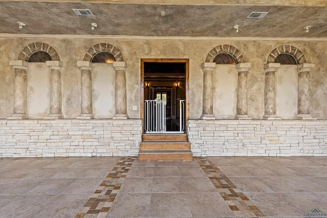 doorway to property featuring visible vents and brick siding