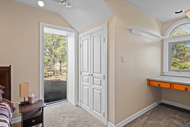 interior space featuring built in desk, carpet, lofted ceiling, and baseboards