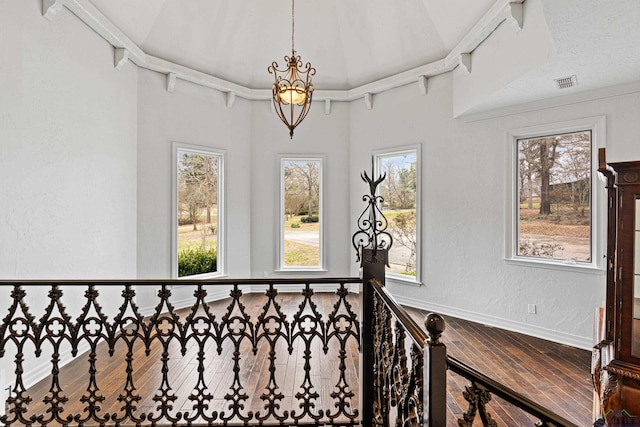 corridor featuring baseboards, visible vents, wood finished floors, and a textured wall