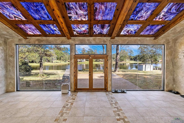 unfurnished sunroom with a water view, a healthy amount of sunlight, beam ceiling, and french doors