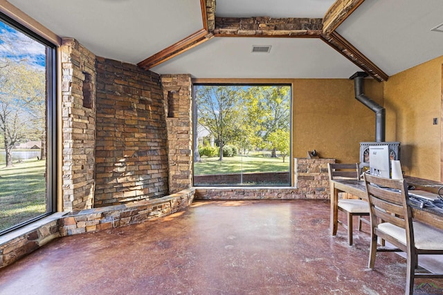 unfurnished sunroom featuring a wood stove, beam ceiling, and visible vents