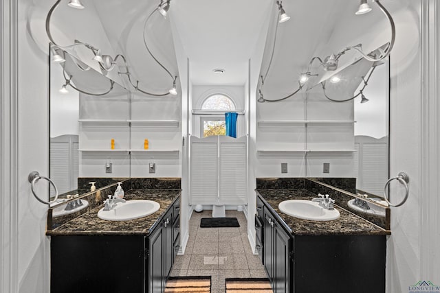 bathroom featuring two vanities, granite finish floor, and a sink