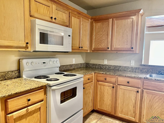 kitchen with light tile patterned flooring, white appliances, sink, and dark stone counters