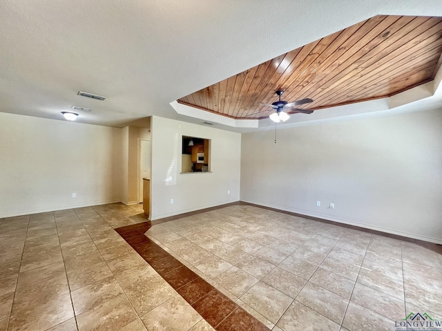 tiled empty room featuring a raised ceiling, ceiling fan, and wood ceiling