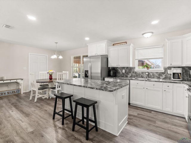 kitchen with a sink, decorative backsplash, wood finished floors, and stainless steel fridge with ice dispenser