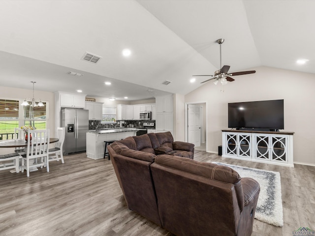 living area featuring light wood-type flooring, visible vents, ceiling fan with notable chandelier, recessed lighting, and vaulted ceiling