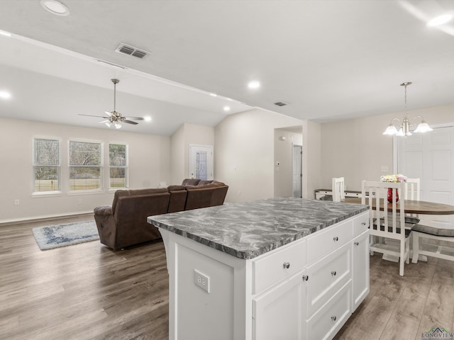 kitchen with visible vents, a center island, lofted ceiling, wood finished floors, and white cabinetry