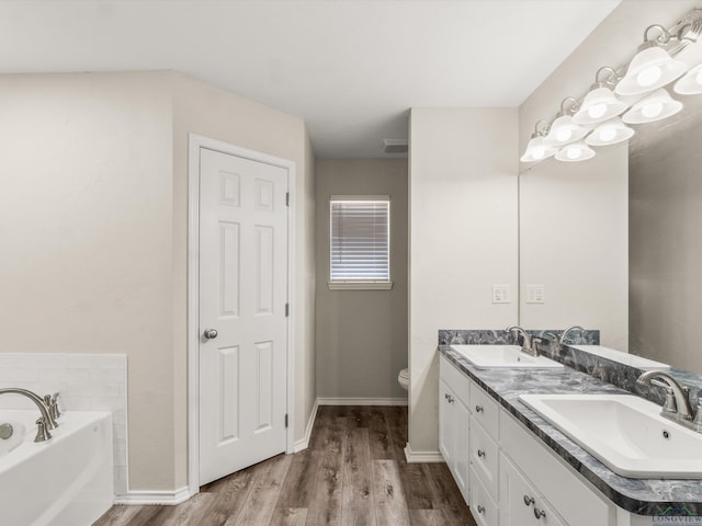 bathroom featuring double vanity, a bath, wood finished floors, and a sink