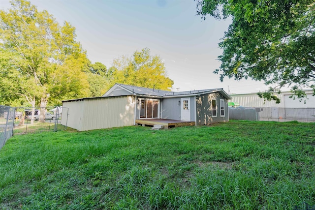 rear view of house with a lawn, a wooden deck, and fence