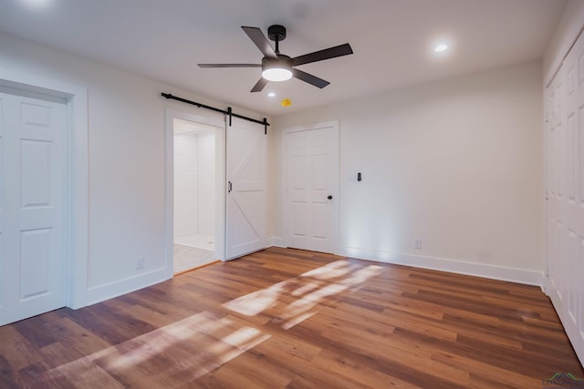 109 Montie St, Longview, TX 75604 - unfurnished bedroom featuring a barn door, recessed lighting, wood finished floors, and baseboards