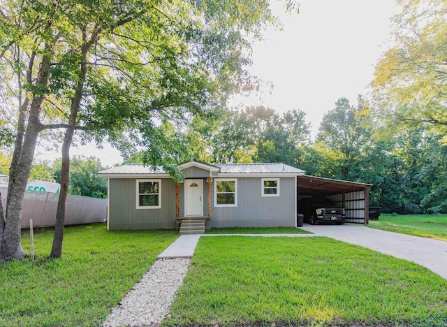 view of front of property featuring an attached carport, a front yard, fence, driveway, and metal roof