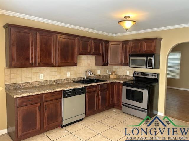42 Wingwood Ter, Marshall, TX 75670 - kitchen featuring appliances with stainless steel finishes, arched walkways, decorative backsplash, ornamental molding, and light tile patterned floors