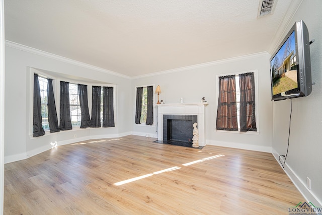 unfurnished living room featuring light hardwood / wood-style floors, ornamental molding, and a textured ceiling