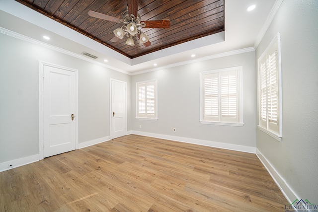 empty room featuring a healthy amount of sunlight, wooden ceiling, crown molding, and a tray ceiling